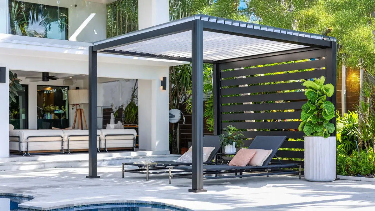 Black K-BANA poolside cabana with white louvers, privacy wall, and two lounge chairs