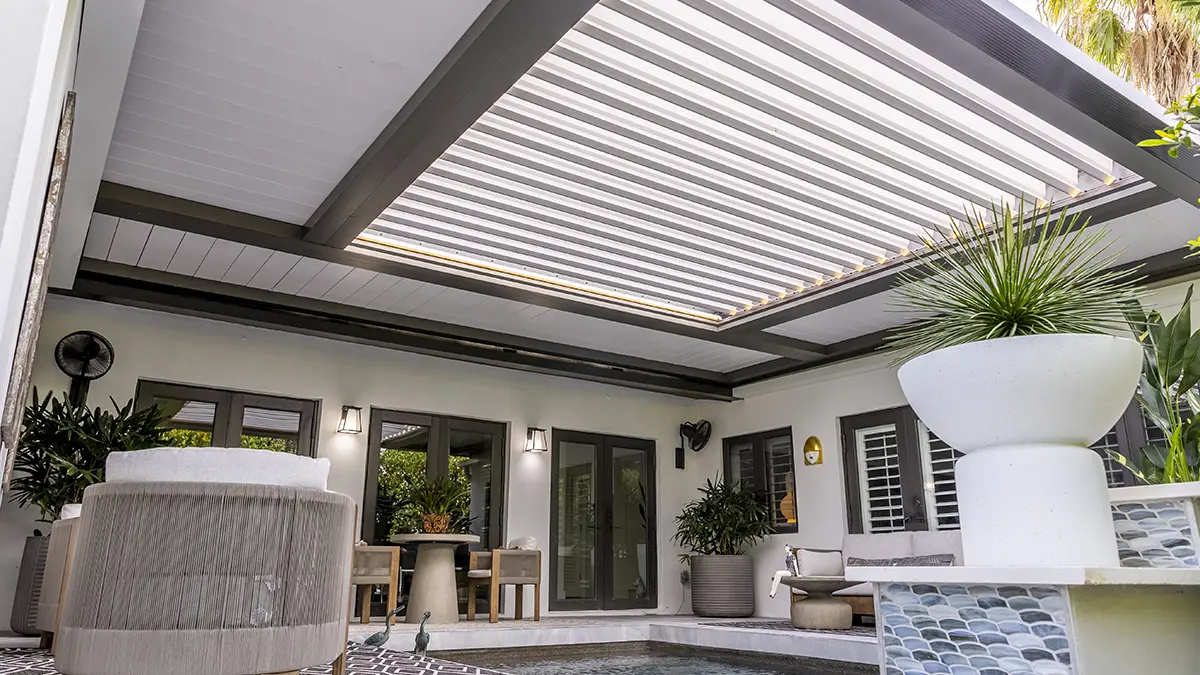 Dark louvered pergola over an outdoor dining area with checkerboard tile