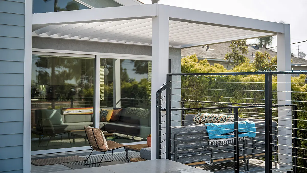 White louvered pergola covering a deck with gray seating and cable railing